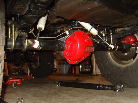 1985 Jeep CJ7 - Underside view of a Jeep's rear axle, a bright red differential cover and suspension components.