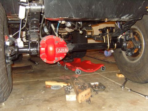 1985 Jeep CJ7 - Close-up view of a vehicle's rear axle and differential, with tools scattered on the garage floor.