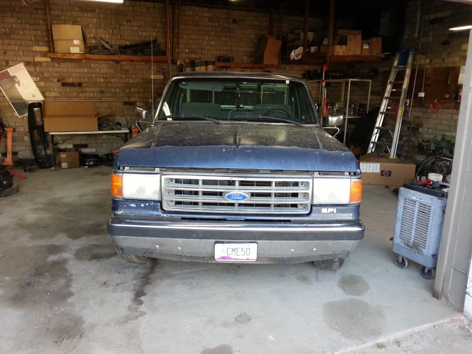 Front view of a blue 1989 Ford F-150 parked in a garage