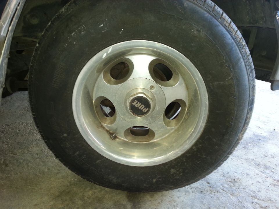 Close-up of a tire on a silver alloy wheel with 'PURE' written on the center cap