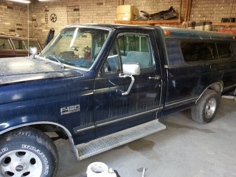 1989 Ford F-150 - This 1989 Ford F-150 pickup truck is parked inside a garage, showing its side profile and camper shell.