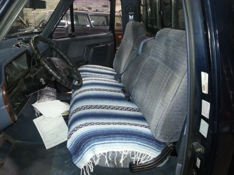 1989 Ford F-150 - Interior view of a 1989 Ford F-150, a blanket on the seats and papers on the floor.