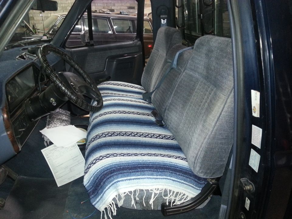 1989 Ford F-150 interior showing driver's seat, passenger seat, and dashboard. Blanket covers the seats