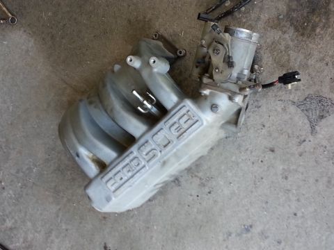 1989 Ford F-150 - Ford 5.0 intake manifold and throttle body assembly shown on a concrete surface.