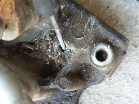 1989 Ford F-150 - Corroded metal part being worked on with a screwdriver, showing a bolt hole.