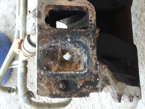 1989 Ford F-150 - Close-up of a heavily rusted metal part with visible hoses and a connector.
