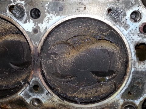 1989 Ford F-150 - Close-up of a used engine cylinder head, showing wear and deposits on the piston tops.