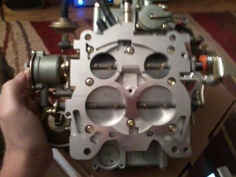 1981 Ford Bronco - A close-up view of a Holley carburetor, held by a person's hand.