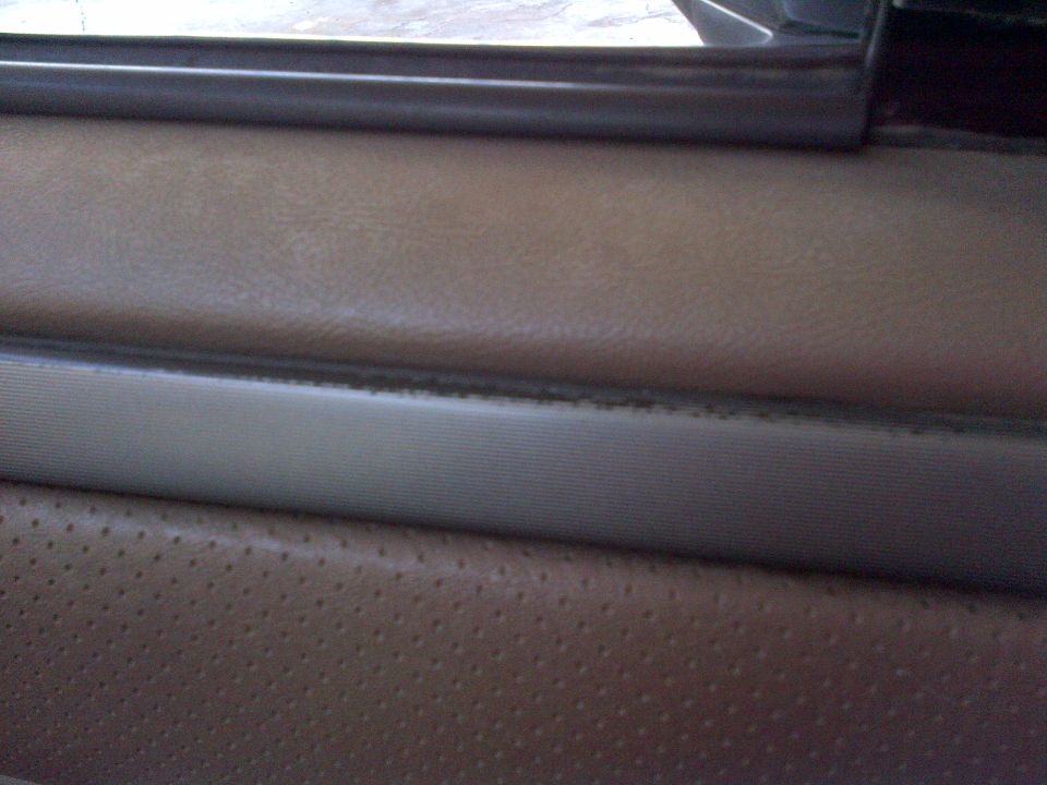 1994 Ford Bronco interior door panel with perforated tan leather and a ribbed trim piece