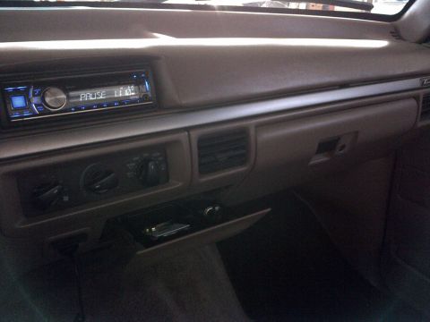 1994 Ford Bronco - The interior dashboard features an aftermarket stereo and climate controls, with a small open compartment below.