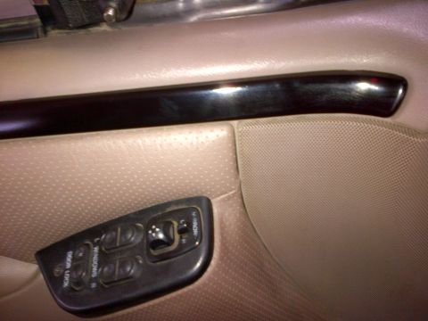 1994 Ford Bronco - Close-up of a vehicle's interior door panel, showing power window controls and a decorative trim piece.