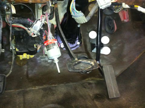 1982 Ford Bronco - View of the interior footwell, showing the brake and accelerator pedals along with a complex wiring harness.