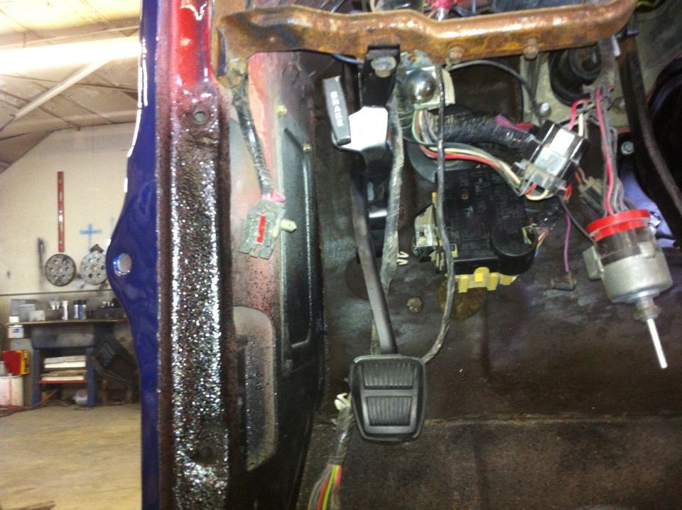 Close-up of vehicle interior showing brake pedal, wiring harness, and dashboard components