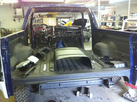 1982 Ford Bronco - The interior and cargo area of a Ford Bronco are shown with many parts removed, indicating it is undergoing restoration or repair.