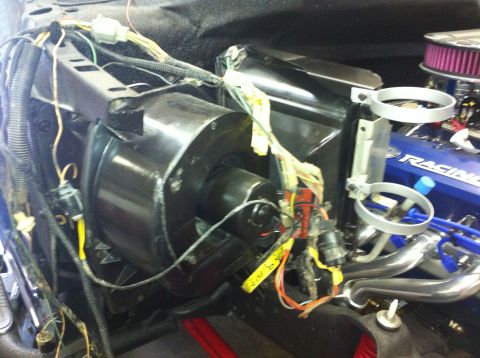 1982 Ford Bronco - Close-up view of the blower motor and associated wiring in an engine bay, alongside a blue valve cover with 'RACING' text.