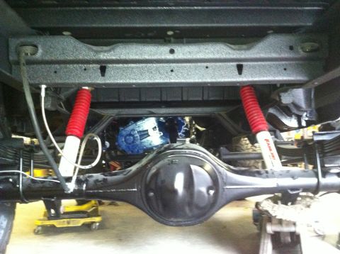 1982 Ford Bronco - Underside view shows rear axle, differential, leaf springs, and red shock absorbers.