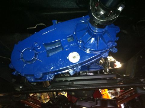 1982 Ford Bronco - A blue painted transfer case is visible from below, attached to a chrome driveshaft.