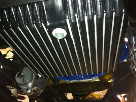 1982 Ford Bronco - Close-up view of a black aftermarket oil pan with prominent silver fins and a circular cap, likely from a vehicle's underside.