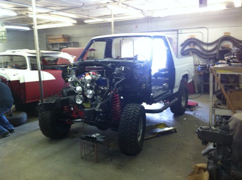 1982 Ford Bronco - This 1980s Ford Bronco is undergoing restoration, showing its chassis and exposed engine with large off-road tires.