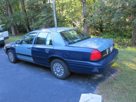 2001 Ford Crown Victoria - A two-tone blue 2001 Ford Crown Victoria is parked on a driveway next to a white vehicle, with trees in the background.