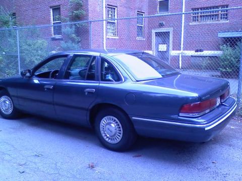 1997 Ford Crown Victoria - A blue 1997 Ford Crown Victoria is parked outdoors in front of a brick building.
