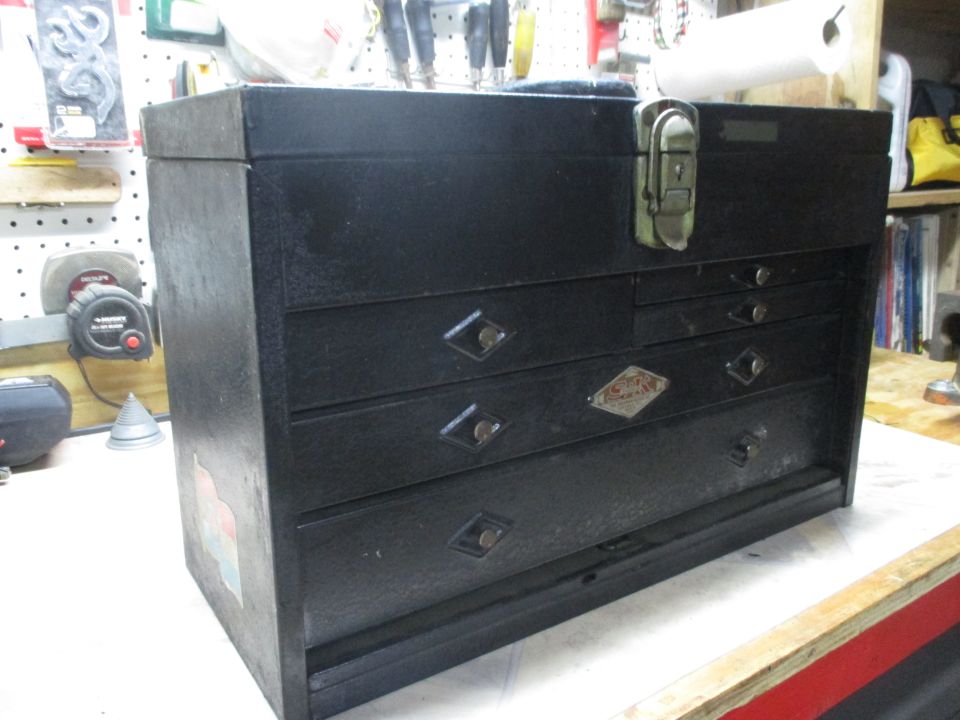 Black metal toolbox with diamond-shaped drawer pulls and a small metal emblem
