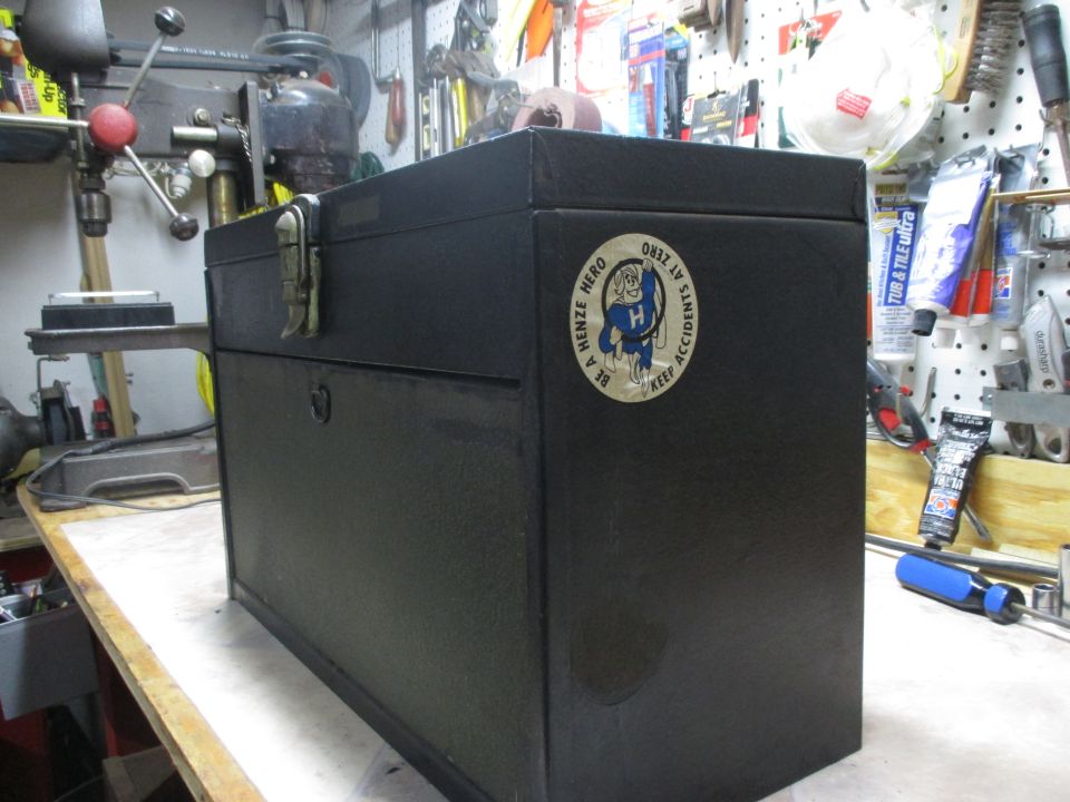 Black metal toolbox with a circular sticker that says 'BE A HENZE HERO KEEP ACCIDENTS AT ZERO'