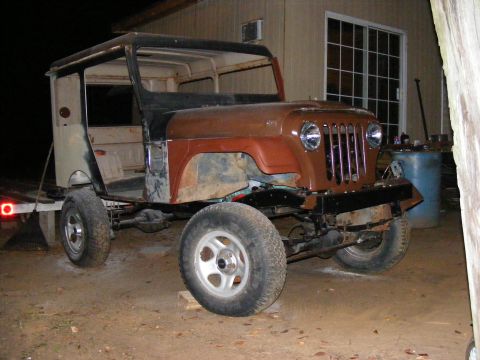 Jeep CJ-5 project vehicle with rust, missing doors, and a hardtop. Front end shows vertical grille