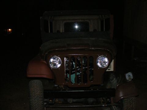 Front view of an old Jeep with a brown grille and round headlights. The vehicle appears to be undergoing resto