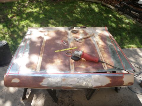 1961 International Scout 800 - A rusty hood is prepped for body work with an angle grinder and hammer visible on its surface.