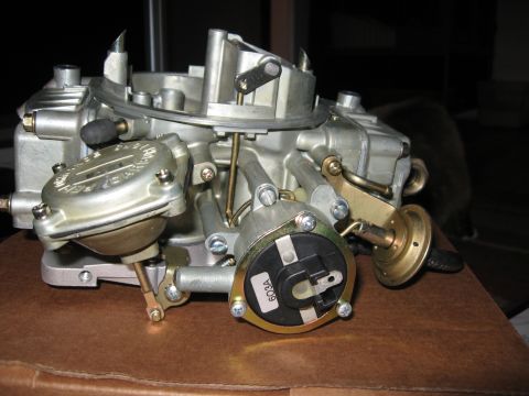 1981 Ford Bronco - A close-up view of a carburetor, showing intricate mechanical details and a visible part number label.
