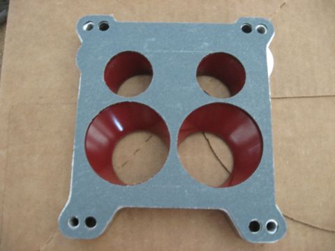 1981 Ford Bronco - A carburetor gasket with a textured gray surface and red inner lining is shown against a cardboard background.