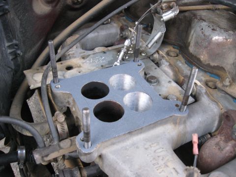 1981 Ford Bronco - Close-up view of a carburetor gasket being fitted onto an engine manifold, with visible SuperMotors.net branding.