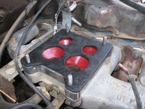 1981 Ford Bronco - Close-up of a carburetor adapter plate installed on an engine's intake manifold.