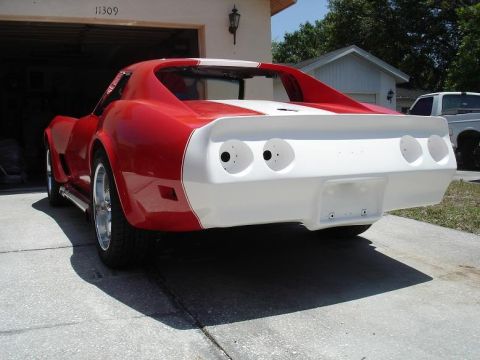 1976 Chevrolet Corvette - Rear view of a red and white 1976 Chevrolet Corvette with racing stripes, parked in a driveway.