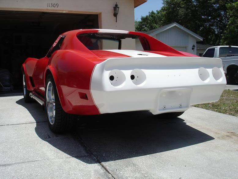 Red and white Chevrolet Corvette rear three-quarter view in driveway during paint and bodywork