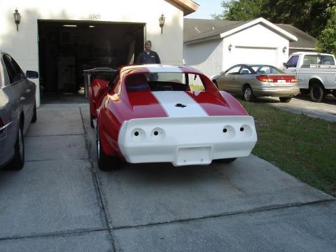 1976 Chevrolet Corvette - A red and white sports car is parked in a driveway with other vehicles present.