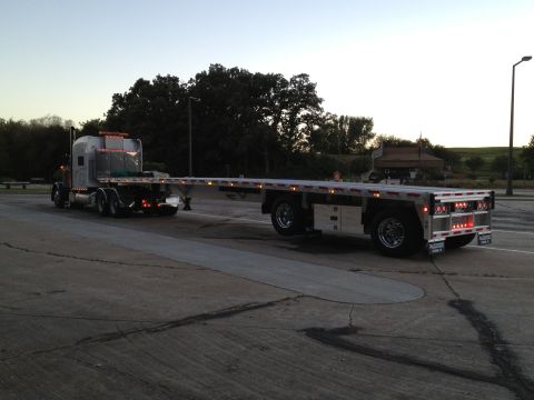 2003 Peterbilt 379 - Peterbilt 379 flatbed semi-truck seen from the rear-side angle at dusk.