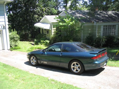 1997 Ford Probe - A dark teal 1997 Ford Probe GTS is parked in a driveway next to a house.