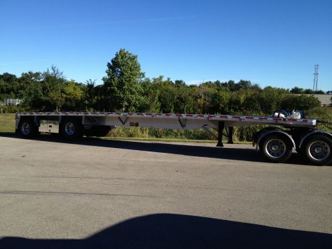 2003 Peterbilt 379 - A long flatbed trailer is shown from the side, parked outdoors on a sunny day.