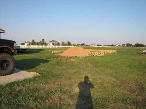 1995 Ford Bronco - A black truck with large tires is parked on a concrete pad in a grassy field with a construction site in the background.