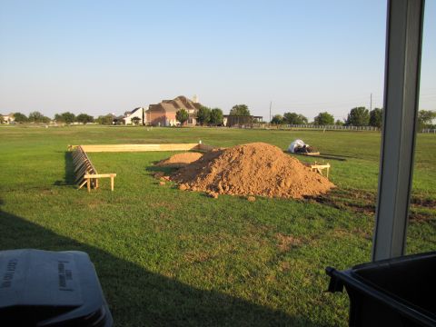 1995 Ford Bronco - A construction site is shown with a wooden frame and a pile of dirt, with houses in the distance.