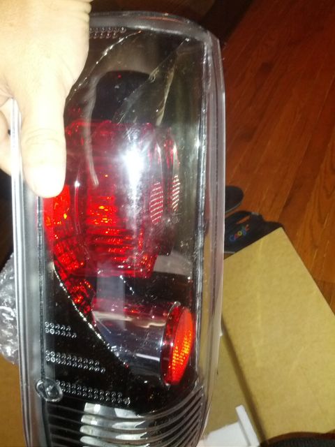 1979 Ford F-150 - A person is holding a vehicle tail light assembly. The part is clear with red lighting elements inside.