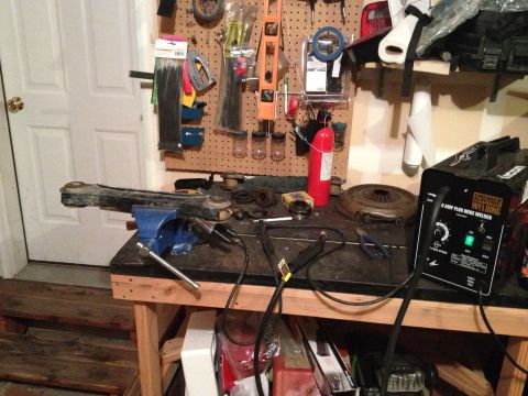 2005 Jeep Wrangler - A single control arm is held in a vise on a workbench, surrounded by various tools and a welding machine.