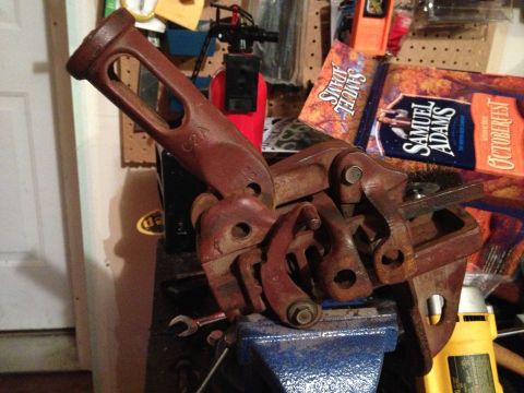 2005 Jeep Wrangler - A close-up of a Hi-Lift jack part, clamped in a vise, with beer advertisements in the background.