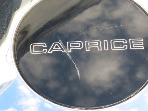 1991 Ford LTD Crown Victoria - A close-up of a scratched chrome wheel cover displaying the word CAPRICE, indicating it is not from a Ford Crown Victoria.