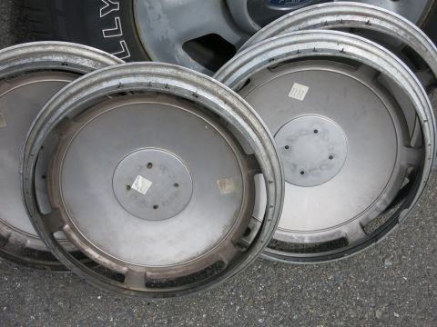1991 Ford LTD Crown Victoria - A collection of four silver hubcaps, with some text visible on the tire sidewall in the background.