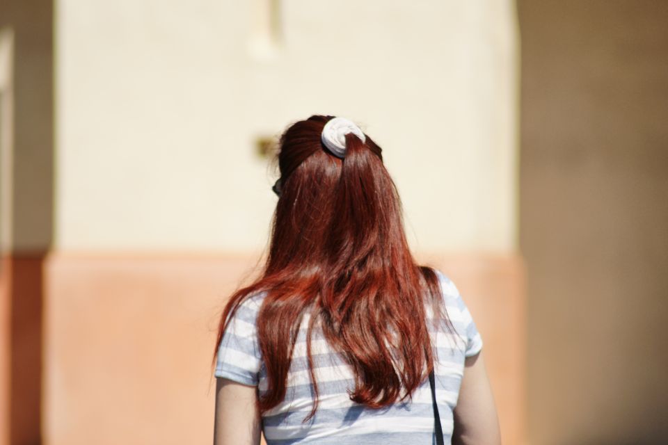 Woman with long red hair tied in a ponytail, wearing a striped shirt