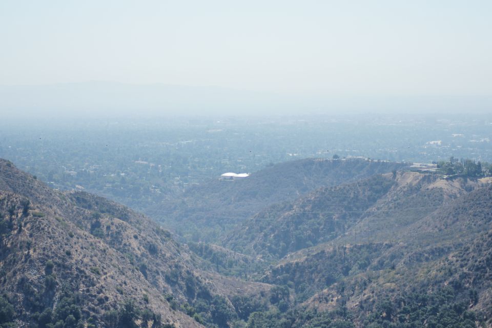 Hazy view of a distant cityscape and hills under a pale sky