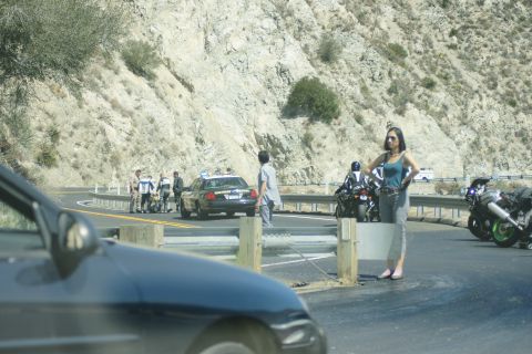 1995 Ford Taurus - A police car and several motorcycles are stopped on a winding mountain road, with a woman standing nearby.